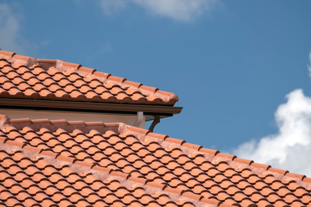 Overlapping rows of yellow ceramic roofing tiles covering residential building roof